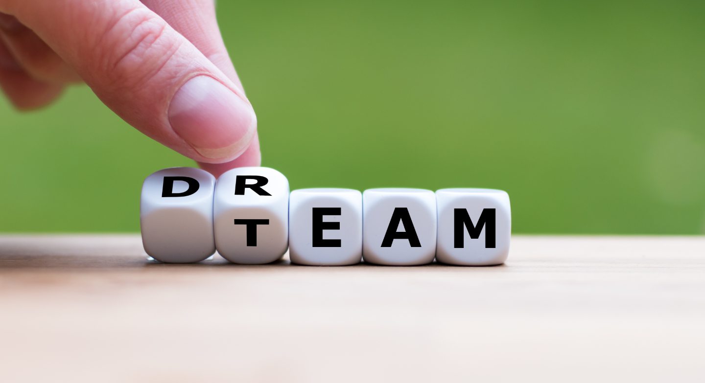 Die Hand dreht einen Würfel und ändert das Wort "Traum" in "Team".